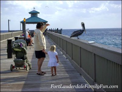 Father, daughter and pelican at the pier