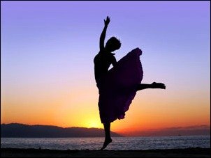 Woman dancing on the beach at sunset